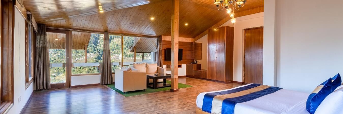 Image of a  suite with a wooden ceiling, walls, and floors, featuring a king size bed and a sitting area  | DLS Serenity Resort and Spa